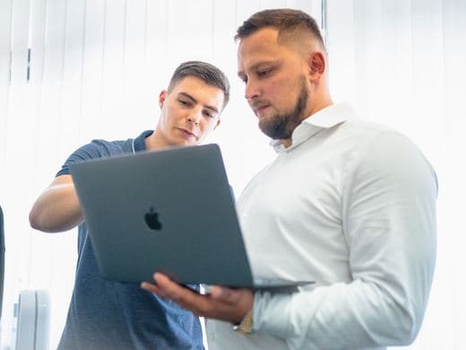 Zwei Mitarbeiter schauen gemeinsam auf einen Laptop