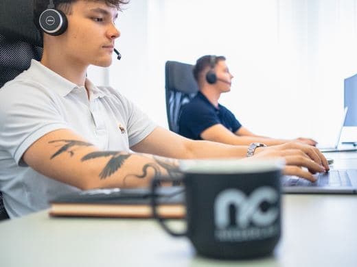 Tasse mit dem Firmenlogo vor einem Arbeitsplatz