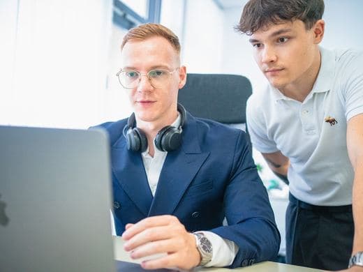 Mitarbeiter im Sakko mit Headset am Schreibtisch