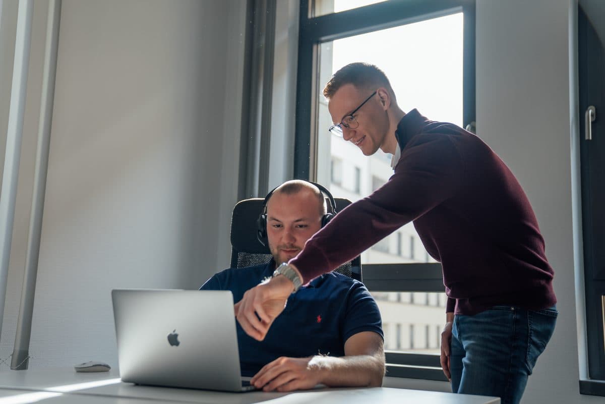 Zwei Mitarbeiter der Niederlag Consulting GmbH gehen gemeinsam ein Telefonskript durch
